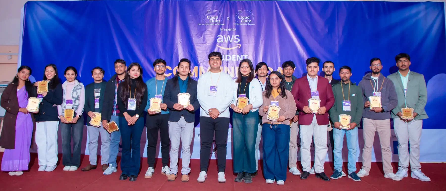 Long line of people holding plaques on a stage in front of the blue event backdrop